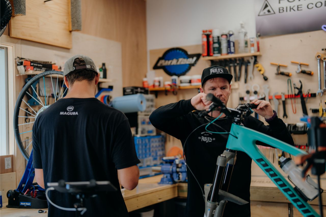 Two mechanics working on a bicycle in a workshop.